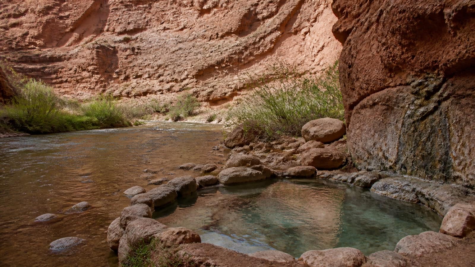 Rock-lined hot spring pool in a desert canyon in Arizona