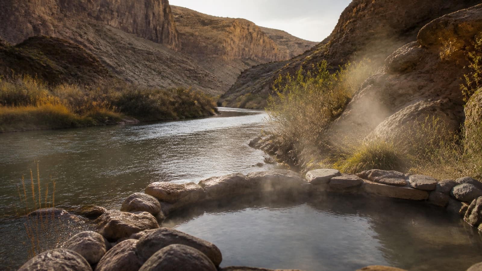 Rock-walled hot spring pool beside a desert river in Far West Texas