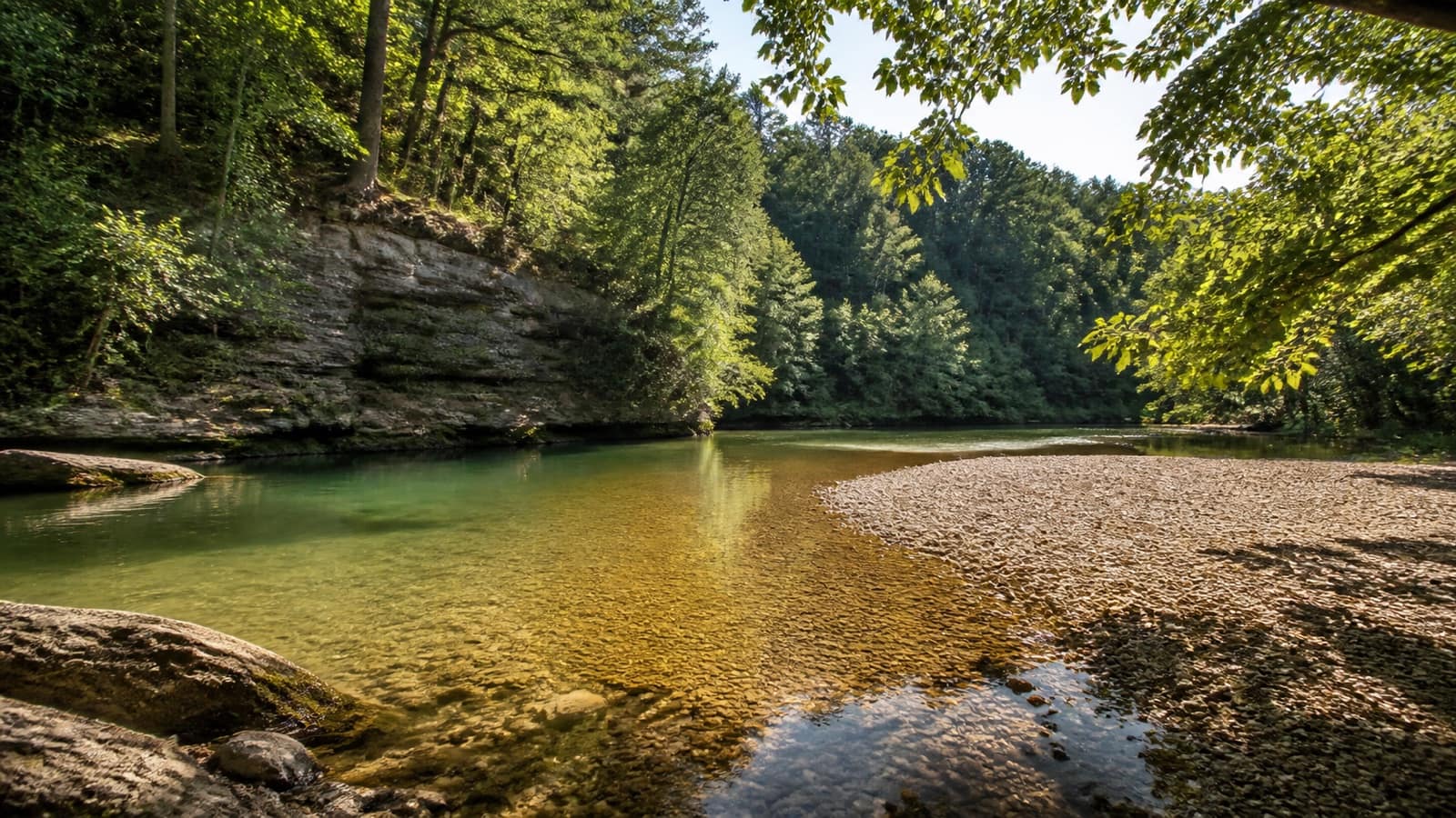 Clear Ozark river swimming hole with a gravel bar and forested bluffs in Arkansas